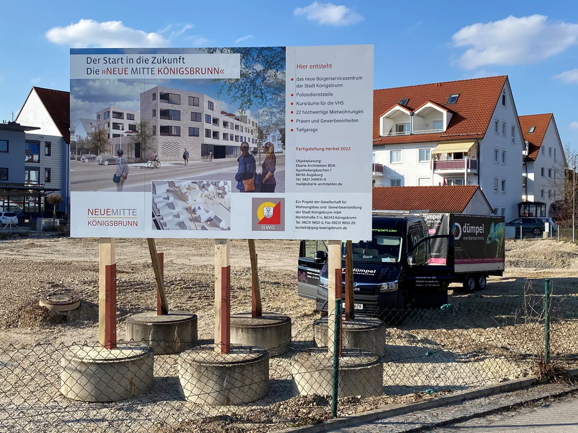 Werbetechnik Dümpel - Augsburg | Baustelle Königsbrunn - Bebauungsplan-Tafel - Wohn-/Gewerbebau-Projekt - LKW und Häuser sichtbar.