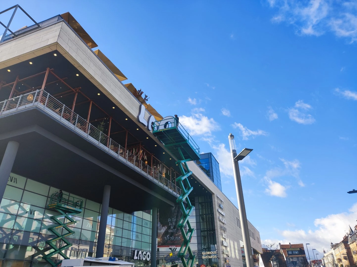 Werbetechnik Dümpel - Augsburg | Modernes Glasgebäude-Baustelle-grüne Aufzüge-Multistore-Bürogebäude-Blauer Himmel-Hochhaus-Stadtarchitektur-Entwicklung.
