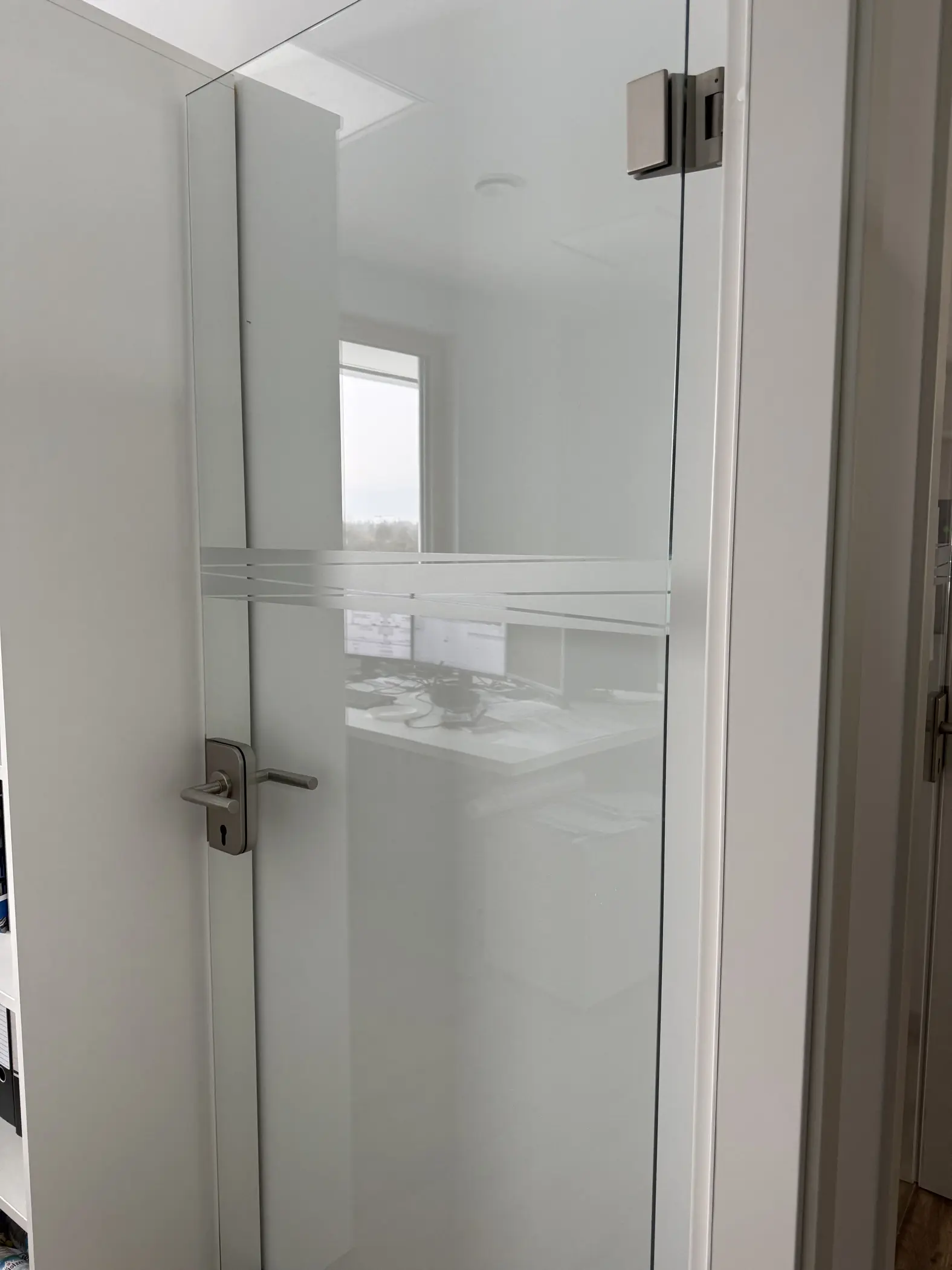 Werbetechnik Dümpel - Augsburg | Milchglas-Bürotür - Metallgriff - moderner Arbeitsbereich - Computer sichtbar - Fensterhintergrund - zeitgenössisches Bürodesign.